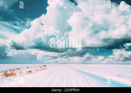 Strada di campagna innevata in inverno nuvoloso giorno. Cielo alterato. Foto Stock