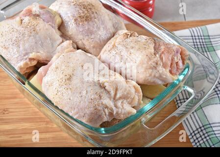 Le cosce di pollo in una teglia da forno sulla parte superiore di a. strato di patate a dadini pronto per il forno Foto Stock