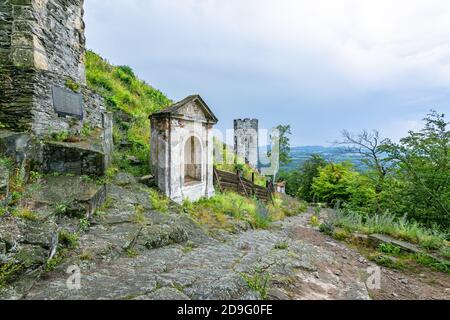 Bezdez, Repubblica Ceca - 19 2020 luglio: Una cappella e una torre, parti del castello medievale in piedi su una collina rocciosa. Giornata estiva con cielo blu e nuvola Foto Stock