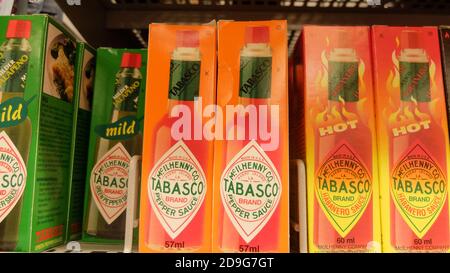 Varietà diversa di salsa Tabasco in un negozio di alimentari scaffale. La salsa Tabasco, è una salsa piccante liquida e proprietaria, fatta di barr matura e mediamente fermentata Foto Stock