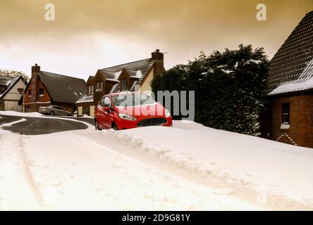 Pontypridd, Galles - Marzo 2018: Vista grandangolare di una deriva da neve su una strada che blocca in una macchina che è parcheggiata sul lato della strada Foto Stock