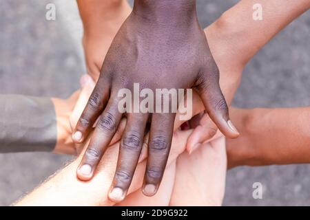 Persone multietniche con mani nere, latine, caucasiche e asiatiche. Amici con una pila di mani che mostrano unità e lavoro di squadra. Tolleranza, lavoro di squadra e formica Foto Stock