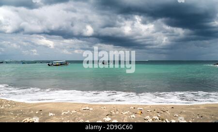 tempesta sul mare, barca da pesca sulla spiaggia. Prima della pioggia in Indonesia, drammatico cielo nuvoloso Foto Stock