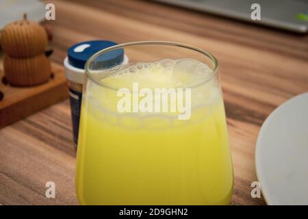 primo piano della compressa effervescente gialla disciolta in un bicchiere di acqua Foto Stock