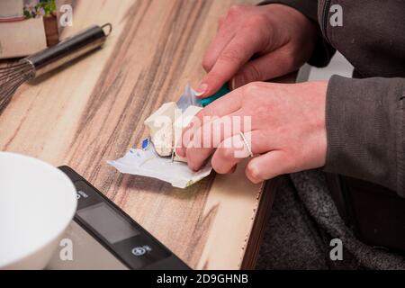 Taglio di un cubo di lievito sulla carta da imballaggio con un coltello piccolo Foto Stock