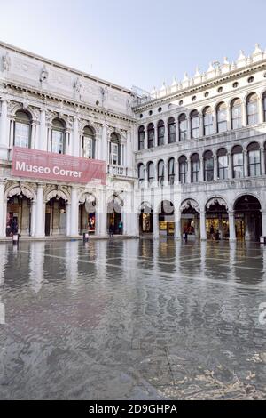 Turisti che scattano fotografie in Piazza San Marco con alta marea, acqua alta, con vista sulla San Marco Procuratie Foto Stock