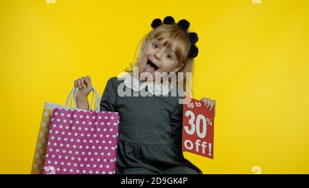 Bambina che mostra fino a 30 per cento di sconto iscrizione segno e shopping borse. Teen allievo sorridente, guardando soddisfatto con i prezzi bassi, lo shopping su Black Friday, Natale o Capodanno Foto Stock