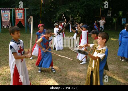 Ragazzi al campo estivo a tema medievale che finge di combattere armi varie Foto Stock