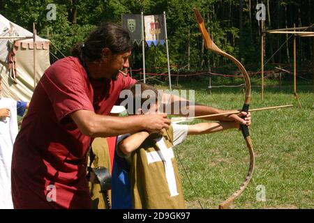 Ragazzi al campo estivo a tema medievale che vengono istruiti sull'uso l'arco e la freccia Foto Stock