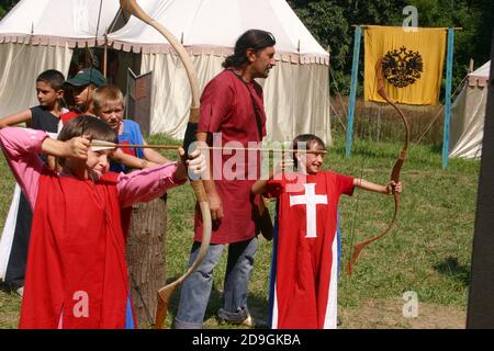 Ragazzi al campo estivo a tema medievale che vengono istruiti sull'uso l'arco e la freccia Foto Stock