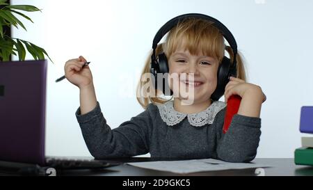 Bambina scolastica ridendo e sorridendo. Lezioni di apprendimento a casa e utilizzo dello smartphone digitale. Ragazza di capretto sull'istruzione di distanza. Studiare durante la quarantena del coronavirus. Sfondo bianco Foto Stock