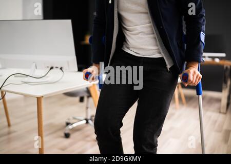 Uomo disabile in piedi con stampelle in ufficio Workplace Foto Stock