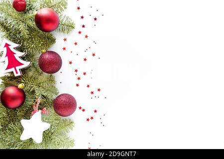 Composizione natalizia con decorazione. Palle di Natale, albero di legno, stella, rami di abete su superficie bianca. Disposizione piatta, vista dall'alto, spazio per la copia Foto Stock