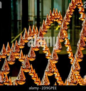 Vista ravvicinata delle gocce di bronzo sospese che sono parte di una installazione dinamica cinetica di arte della pioggia Foto Stock