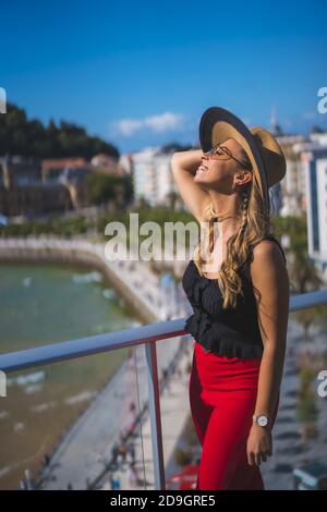 Bella donna caucasica bianca felicemente in piedi sul balcone di la camera dell'hotel con vista mare Foto Stock