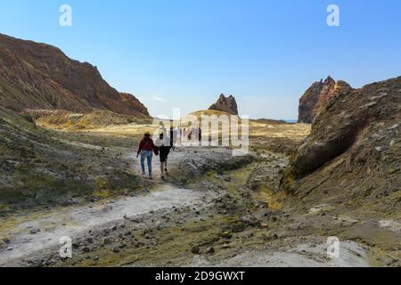 Un gruppo che cammina attraverso il paesaggio arido e colorato di zolfo di White Island, un vulcano attivo nella baia di Plenty, Nuova Zelanda Foto Stock