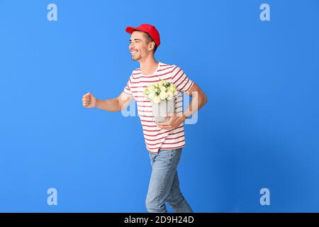 Uomo di consegna running con bouquet di fiori su sfondo colorato Foto Stock