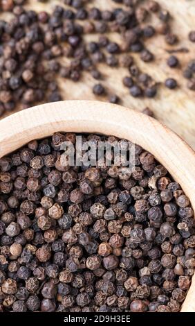 pepe nero speziato sparso su un vecchio tavolo di legno Foto Stock