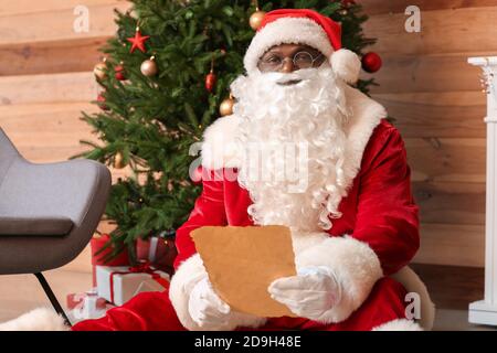 Babbo Natale afroamericano che legge la lettera a casa Foto Stock