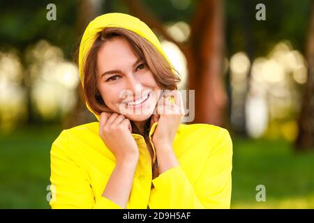 Bella giovane donna con impermeabile nel parco Foto Stock