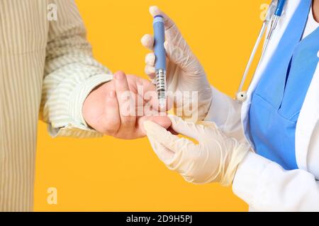 Medico che prende il campione di sangue di anziano diabetico uomo a colori sfondo Foto Stock