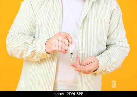 Uomo diabetico anziano che prende il campione di sangue con la penna di lancet sopra sfondo a colori Foto Stock