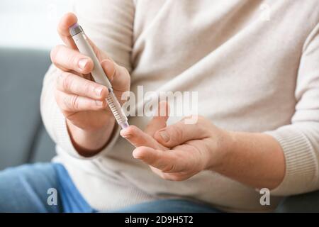 Uomo diabetico anziano che prende il campione di sangue con la penna di lancet a. casa Foto Stock