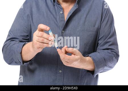 Uomo diabetico anziano che prende il campione di sangue con la penna di lancet sopra sfondo bianco Foto Stock