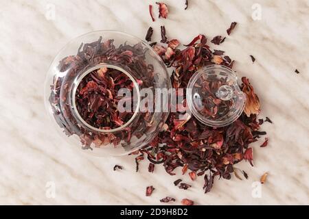 Vasetto con tè secco all'ibisco sul tavolo Foto Stock