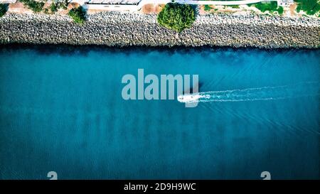 Vista aerea dall'alto di una barca bianca che si muove lungo il costa Foto Stock