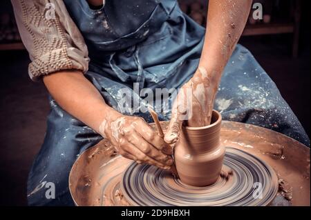 Scultore artigiano lavora con argilla sulla ruota di un vasaio e al tavolo con gli attrezzi. Arte ceramica concetto. Primo piano. Foto Stock