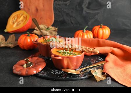 Gustosa zuppa di crema di zucca in pentole su sfondo scuro Foto Stock