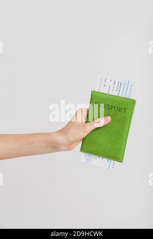 Mano femminile con passaporto e biglietto su sfondo chiaro Foto Stock