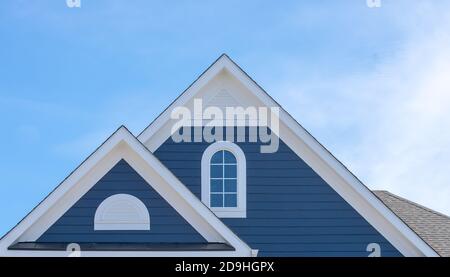 Finestra soffitta bianca su lato blu, tegola, corbel, louvre su una nuova costruzione di lusso casa singola americana famiglia nella costa orientale degli Stati Uniti d'America con blu Foto Stock