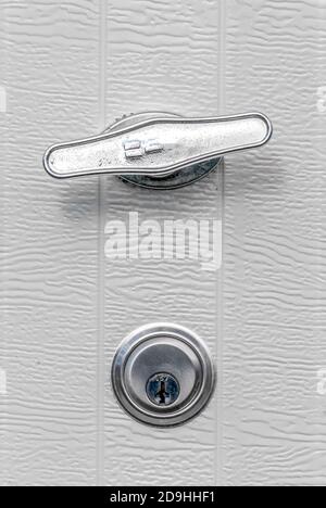 Maniglia e serratura della porta del garage color argento su sfondo bianco Foto Stock