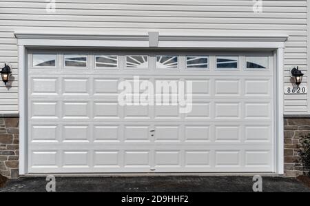 Doppia auto classica isolato in acciaio pannello rialzato porta del garage incorniciato con un rivestimento bianco per aggiungere accento, su una nuova casa americana Foto Stock