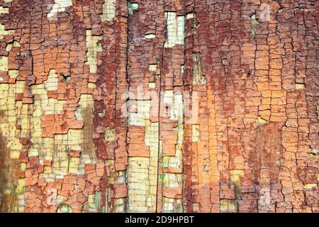 Vernice marrone incrinata su sfondo di legno. Superficie di legno rossa incrinata. Sfondo a trama resistente agli agenti atmosferici Foto Stock