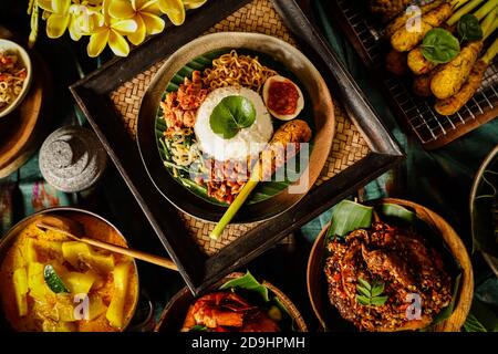 Nasi Campur Bali. Pasto balinese di riso con pollo sminuzzato, insalata di verdure, arachidi, satay, uova e tagliatelle fritte. Foto Stock