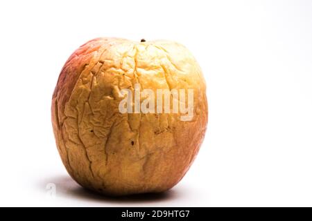 Mela gialla e rossa con rughe profonde su sfondo bianco. Concetto di invecchiamento. Foto Stock