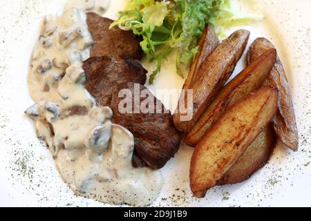 Medaglioni di manzo con salsa di funghi e patate al forno Foto Stock