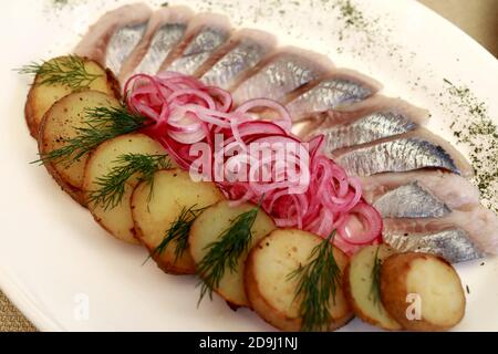 Aringhe tagliate a fette con patate al forno e cipolle su piatto Foto Stock
