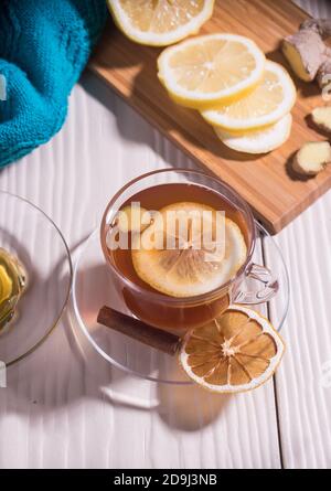 Tè vitaminico con limone e zenzero in una tazza di vetro, sfondo bianco.primo piano. Orientamento verticale. Foto Stock