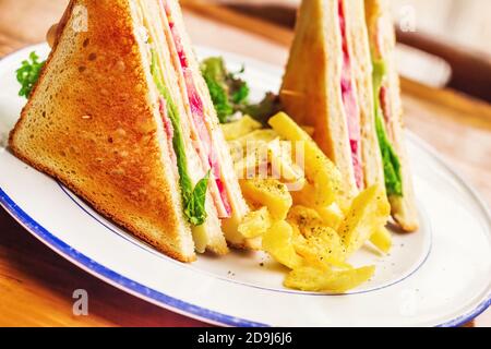 Club sandwich servito con patatine fritte, dof poco profondo Foto Stock