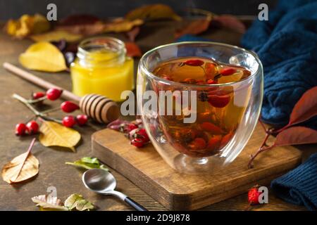 Sana bevanda vitaminica invernale. Tè caldo di rosa con miele e frutta secca su un tavolo di legno. Foto Stock