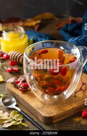 Sana bevanda vitaminica invernale. Tè caldo di rosa con miele e frutta secca su un tavolo di legno. Foto Stock