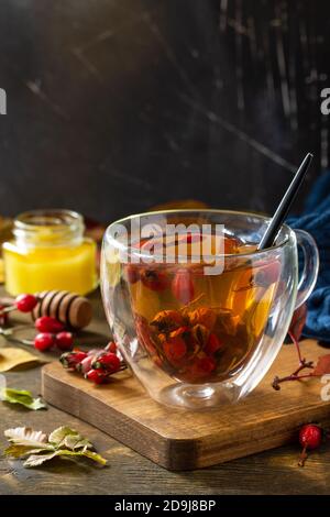 Sana bevanda vitaminica invernale. Tè caldo di rosa con miele e frutta secca su un tavolo di legno. Spazio di copia. Foto Stock