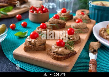 Tartine con pane di segala, pate di fegato, pomodori ciliegini. Colazione snack. Foto Stock