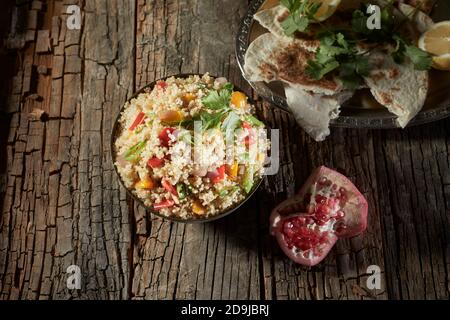 Insalata mista di couscous e quinoa con melograno e piatto pane visto in alto su un vecchio rustico o annata tavolo con legno fessurato e copysp Foto Stock