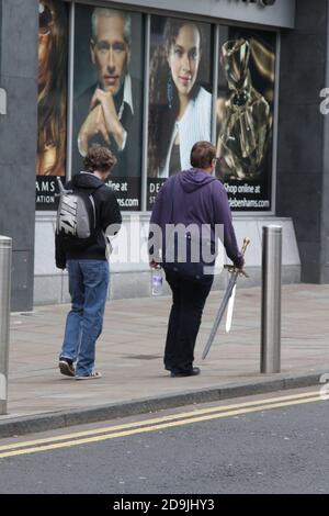 Ayr, Ayrshire, Scozia, Regno Unito. Due adolescenti che camminano su strada portando una spada giocattolo Foto Stock