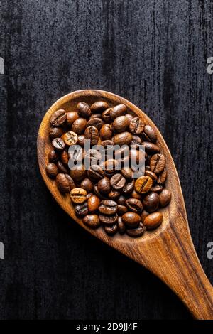 Chicchi di caffè arrostiti su un cucchiaio di legno. Vista dall'alto. Foto Stock